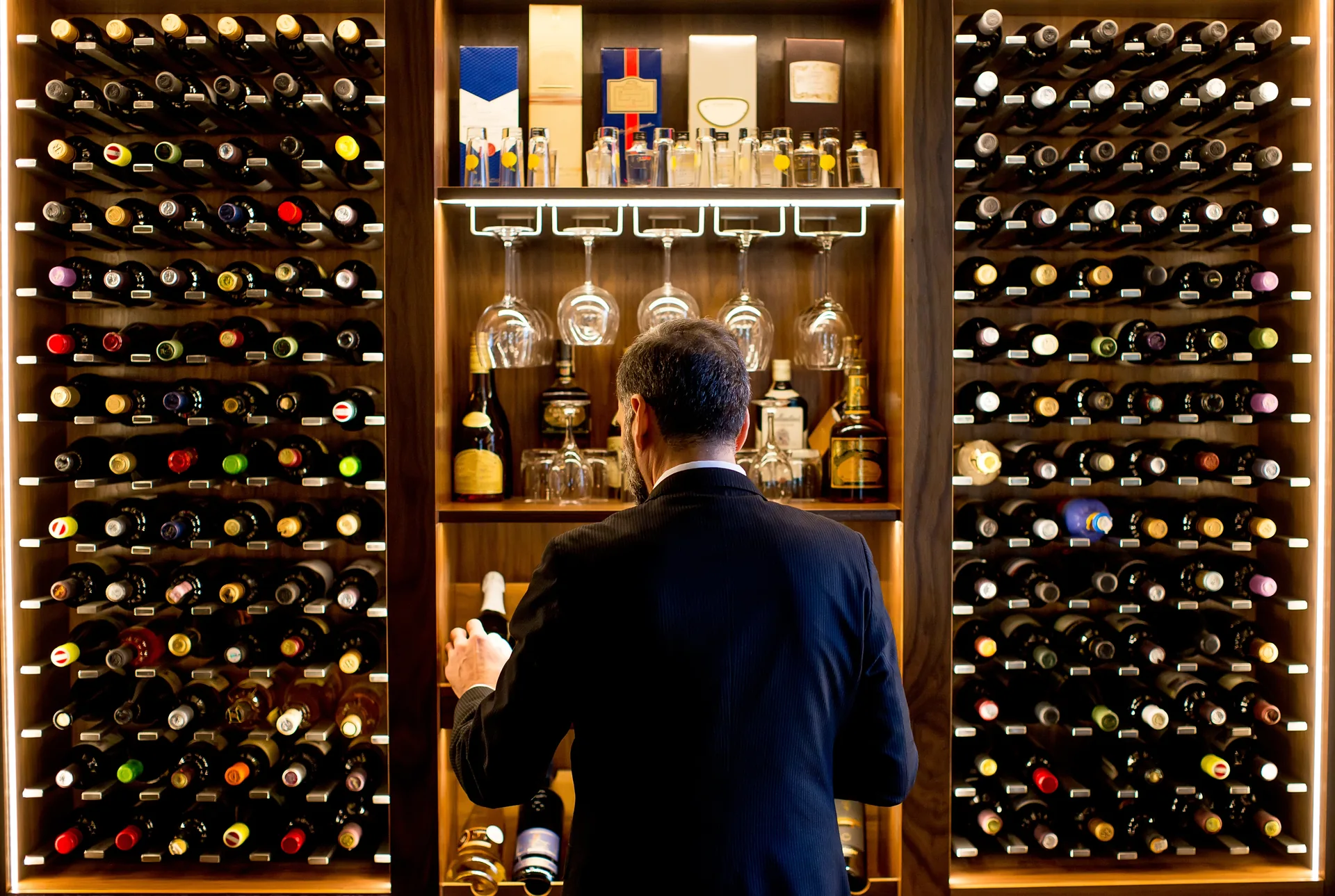 A buyer selecting a bottle from a wall of wine in a retail store